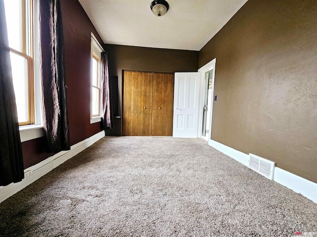 unfurnished bedroom featuring multiple windows, carpet floors, and a closet