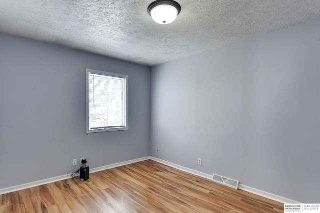 unfurnished room with a textured ceiling and light hardwood / wood-style floors