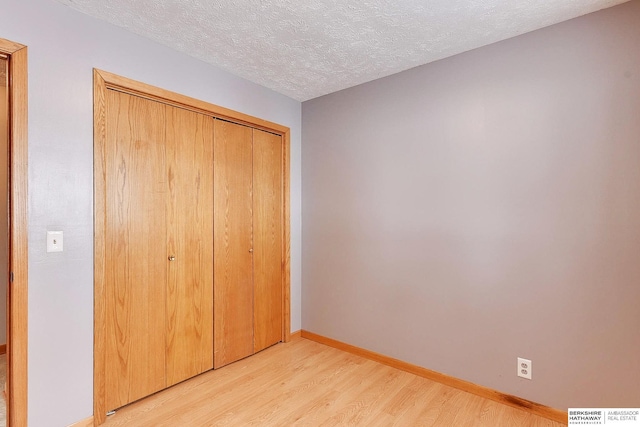 unfurnished bedroom featuring light hardwood / wood-style floors, a closet, and a textured ceiling