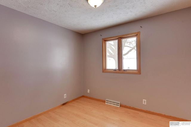 unfurnished room with a textured ceiling and light hardwood / wood-style flooring