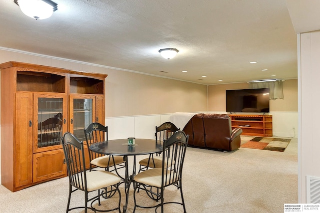 carpeted dining area with a textured ceiling and ornamental molding