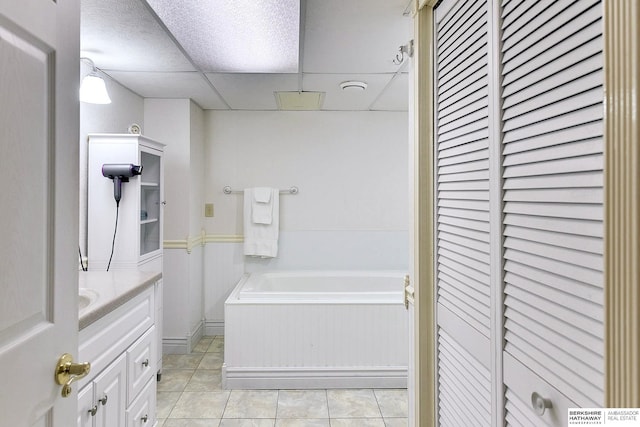 bathroom with tile patterned floors, a drop ceiling, vanity, and a bathing tub