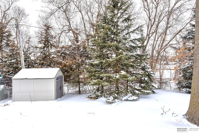 snowy yard featuring a storage shed