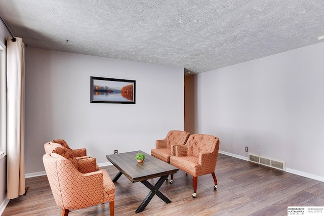 living area featuring a textured ceiling and hardwood / wood-style floors