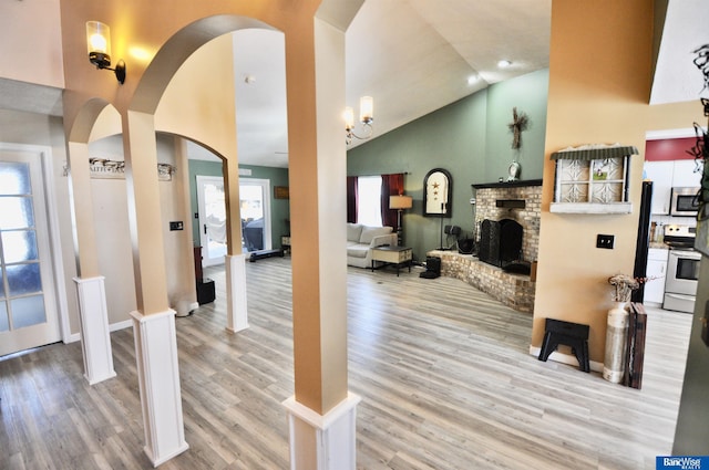 interior space featuring a brick fireplace, wood-type flooring, and high vaulted ceiling