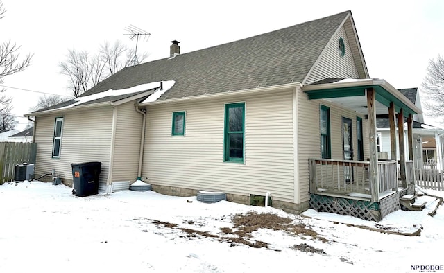 snow covered property featuring cooling unit and covered porch