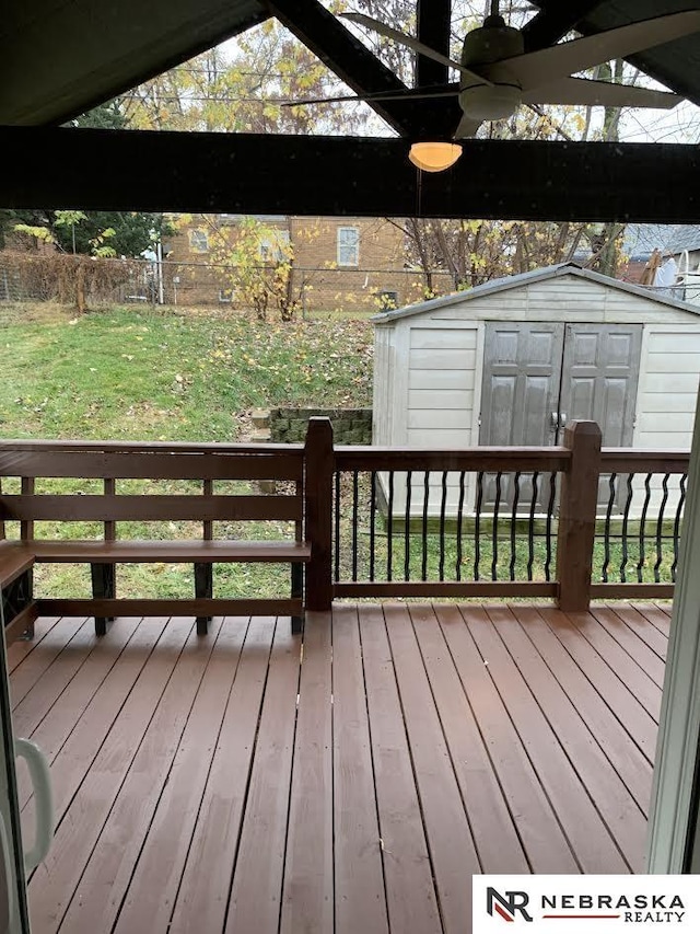 wooden deck with a lawn, ceiling fan, and a storage shed