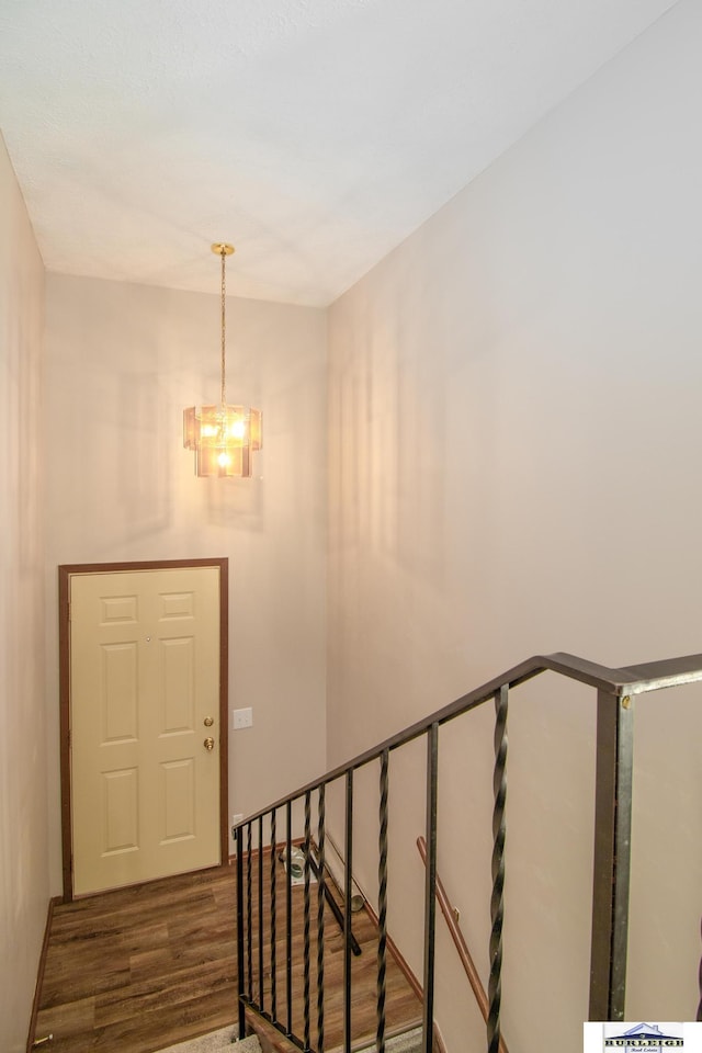 stairs featuring hardwood / wood-style floors and a notable chandelier