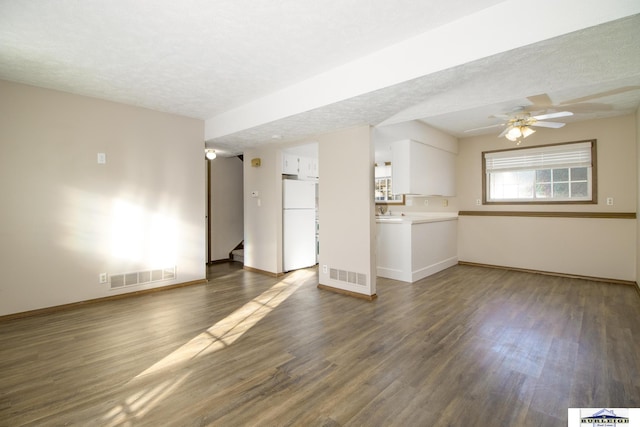 unfurnished living room with ceiling fan, dark wood-type flooring, and a textured ceiling