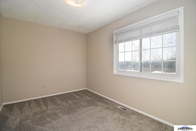 carpeted empty room featuring a textured ceiling