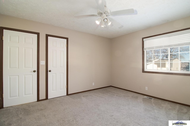 unfurnished bedroom featuring light carpet, ceiling fan, and a textured ceiling