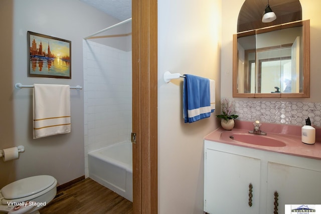 full bathroom with tiled shower / bath combo, toilet, wood-type flooring, and vanity