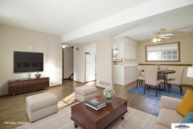 living room with a textured ceiling, hardwood / wood-style floors, and ceiling fan