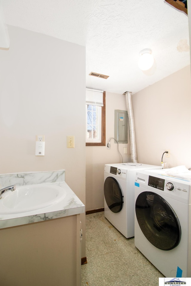 laundry area with electric panel, sink, washer and clothes dryer, and a textured ceiling
