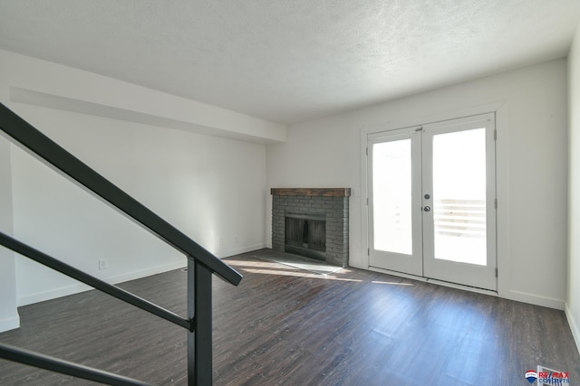 unfurnished living room featuring a textured ceiling, french doors, a fireplace, and dark hardwood / wood-style flooring