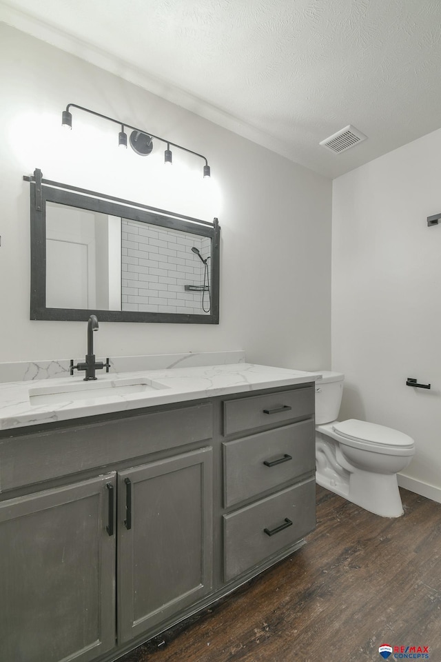 bathroom featuring hardwood / wood-style flooring, toilet, vanity, and a textured ceiling