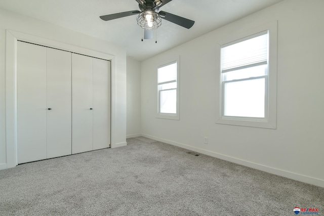 unfurnished bedroom featuring light carpet, a closet, and ceiling fan