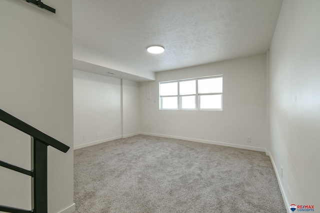 carpeted empty room with a textured ceiling