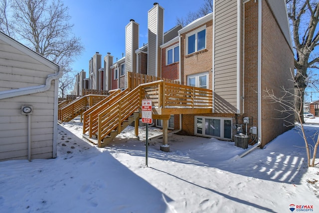 snow covered rear of property featuring a wooden deck