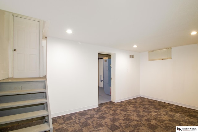 basement featuring refrigerator and dark colored carpet