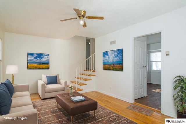 living room featuring ceiling fan, dark wood-type flooring, and a textured ceiling