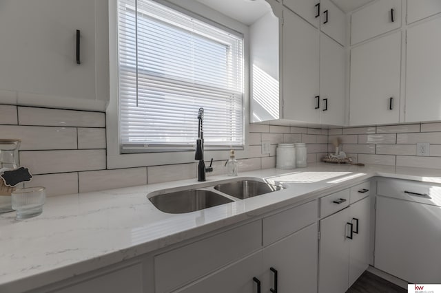 kitchen with sink, white cabinetry, light stone countertops, and backsplash