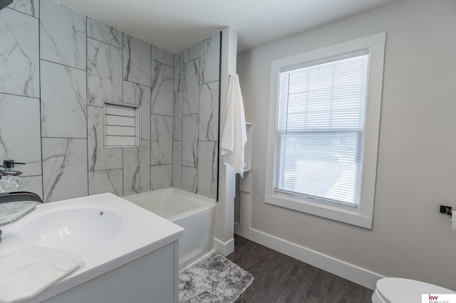 full bathroom featuring hardwood / wood-style flooring, vanity, tiled shower / bath, and toilet