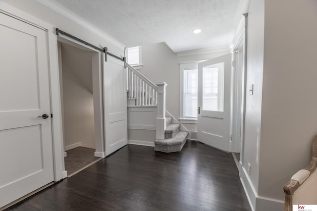 entrance foyer featuring a textured ceiling, dark wood-type flooring, and a barn door