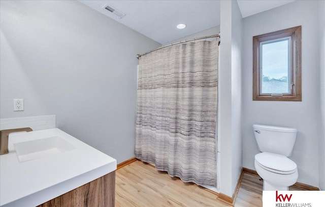 bathroom featuring toilet, baseboards, visible vents, and wood finished floors