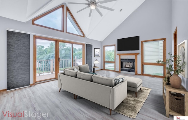 living area featuring ceiling fan, high vaulted ceiling, a tile fireplace, light wood-style flooring, and baseboards