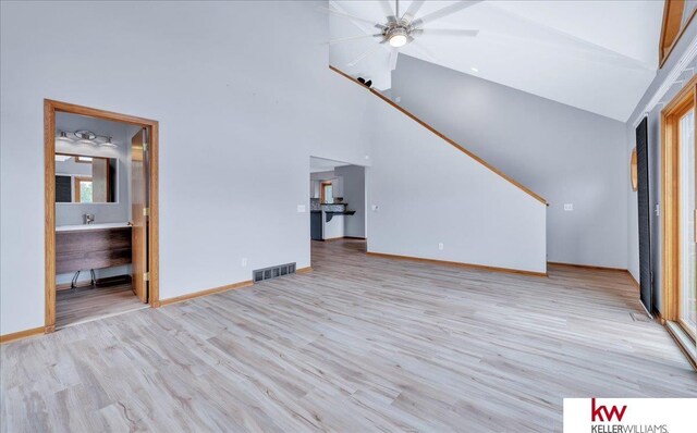 unfurnished living room featuring high vaulted ceiling, light wood-type flooring, visible vents, and baseboards