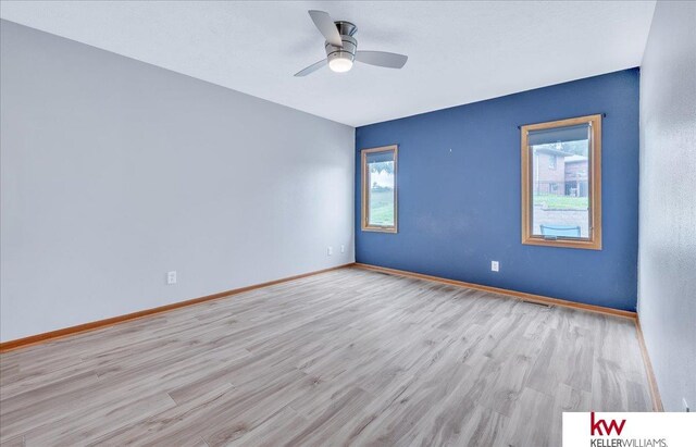 unfurnished room with wood finished floors, a wealth of natural light, and baseboards