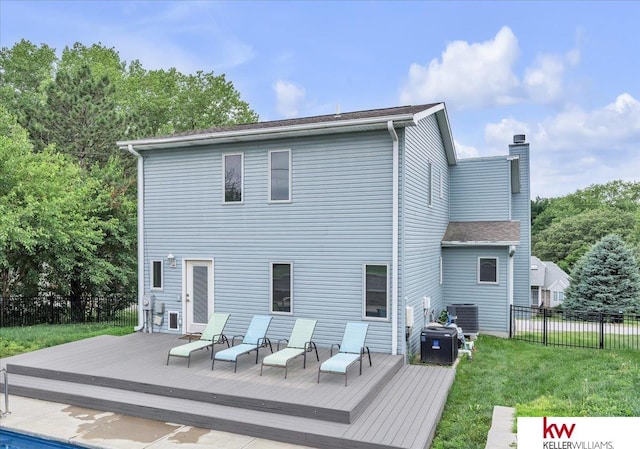 rear view of house featuring a lawn, a chimney, a wooden deck, and fence