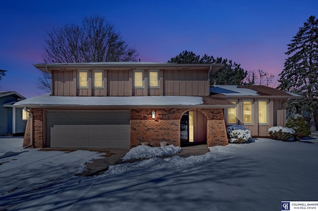 view of front facade featuring concrete driveway, an attached garage, brick siding, and board and batten siding