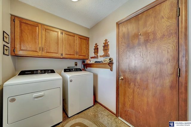 laundry area with washer and dryer, cabinets, and a textured ceiling