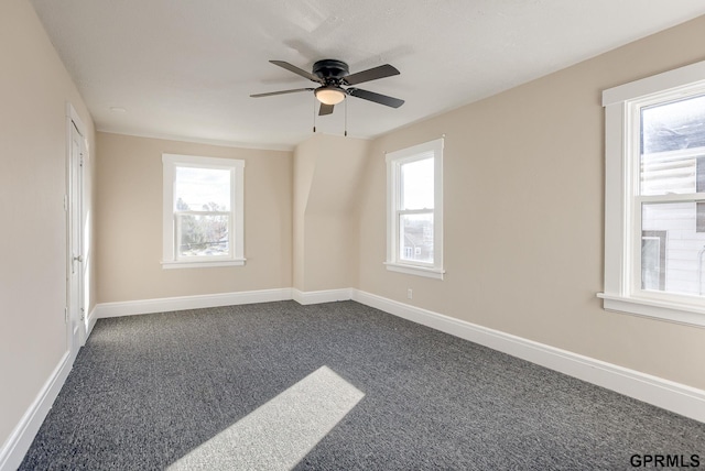 unfurnished room with ceiling fan, plenty of natural light, and dark colored carpet