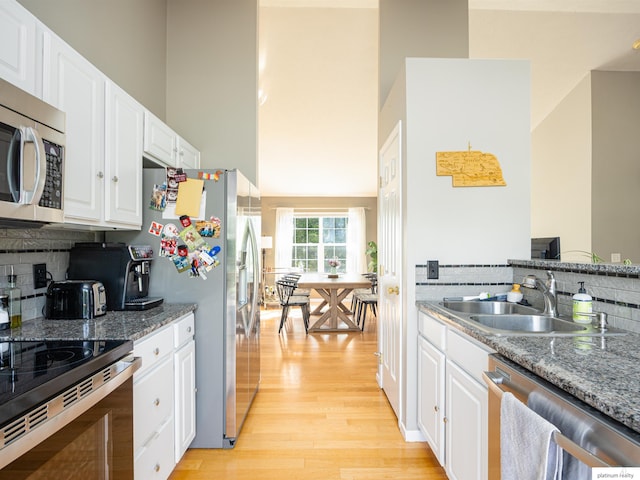 7112 S 177th St, Omaha, NE 68136 - kitchen with appliances with stainless steel finishes, light wood finished floors, white cabinets, backsplash, and a high ceiling