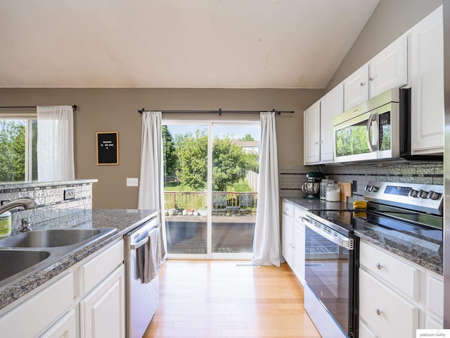 7112 S 177th St, Omaha, NE 68136 - kitchen featuring appliances with stainless steel finishes, light wood-type flooring, backsplash, white cabinetry, and vaulted ceiling