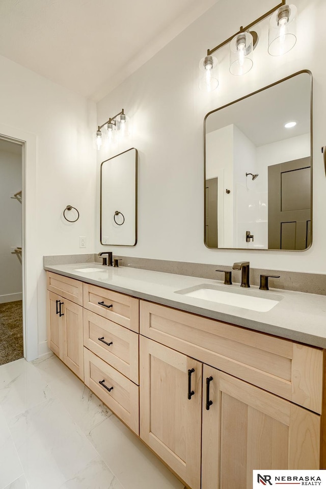 bathroom featuring marble finish floor, double vanity, and a sink