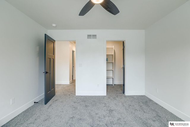 unfurnished bedroom with baseboards, a spacious closet, visible vents, and carpet flooring