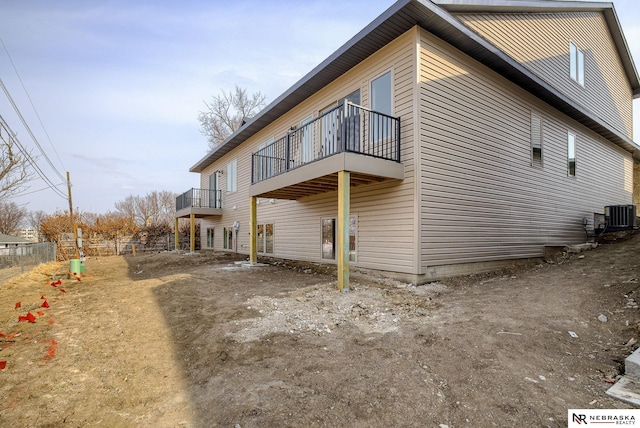 view of home's exterior with central AC unit, fence, and a balcony