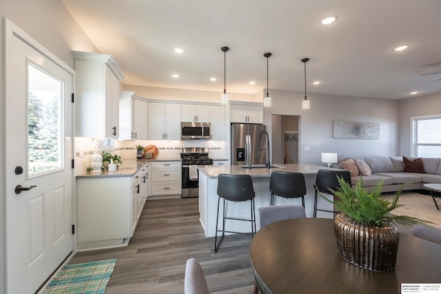 kitchen featuring stainless steel appliances, a breakfast bar, open floor plan, light countertops, and tasteful backsplash