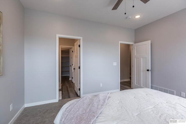 carpeted bedroom with a walk in closet, recessed lighting, visible vents, ceiling fan, and baseboards