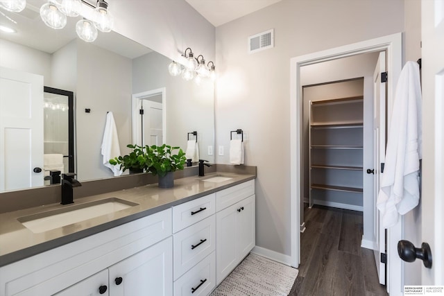 bathroom featuring double vanity, visible vents, a sink, and wood finished floors