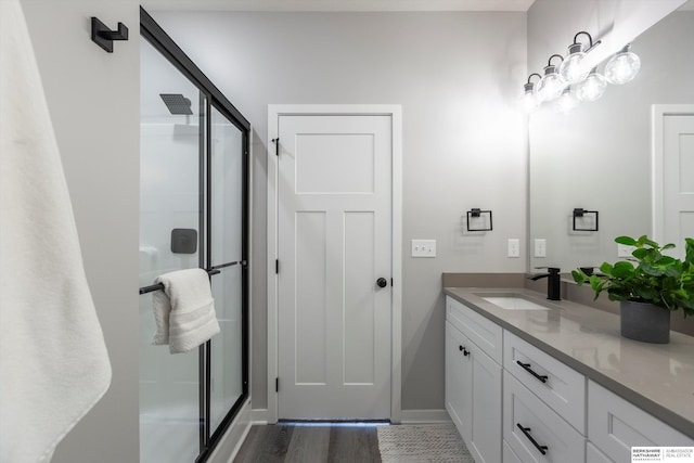 full bath with baseboards, a shower stall, vanity, and wood finished floors