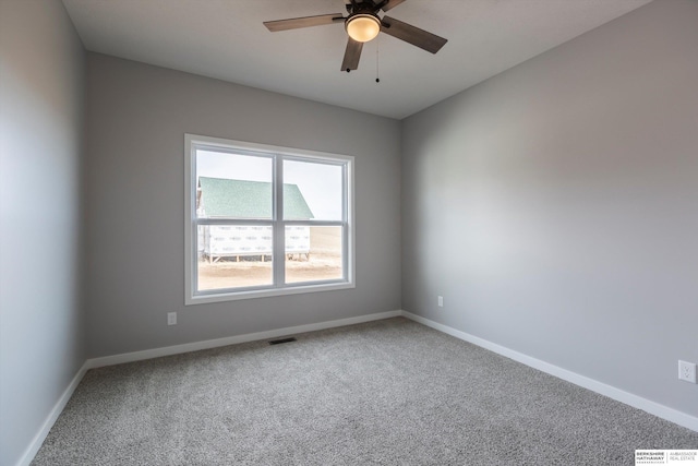 carpeted empty room featuring ceiling fan, visible vents, and baseboards