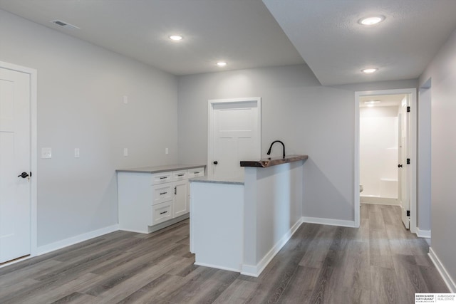 kitchen with recessed lighting, dark wood-type flooring, visible vents, white cabinetry, and baseboards