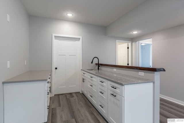 kitchen featuring recessed lighting, dark wood-type flooring, white cabinets, a sink, and a peninsula