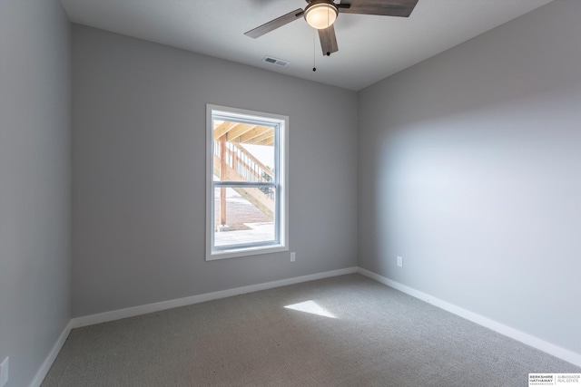 empty room with ceiling fan, carpet floors, visible vents, and baseboards