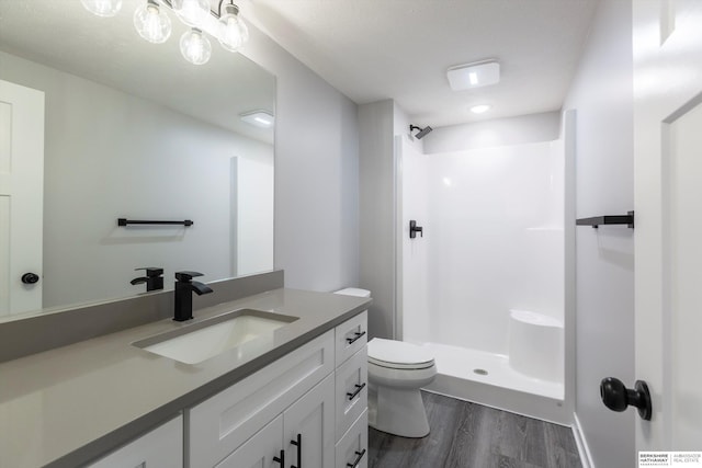 full bathroom featuring vanity, a shower stall, toilet, and wood finished floors